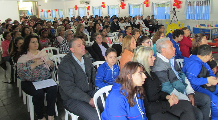 Famílias e convidados no salão, para a festa de apresentação do projeto.